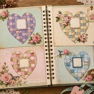 Op de afbeelding: Open scrapbook met vier hartvormige pagina's. Elk hart heeft een patchwork-ontwerp en een leeg vierkant voor foto's. Versieringen zijn roze rozen, vogels en kant. De scrapbook is gebonden met een spiraalbinding.