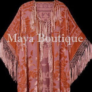 Peut inclure: Un long kimono rose et orange avec un motif floral et une bordure en franges. Le kimono a un col en V et est fait d'un tissu doux et soyeux. Le texte "Maya Boutique" est visible sur le devant du kimono.