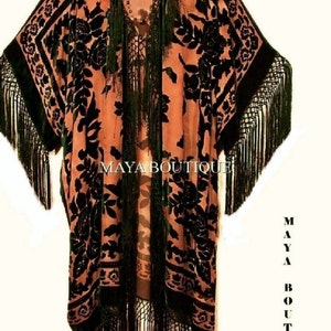 Peut inclure: Un long kimono noir et orange avec un motif floral et une bordure à franges. Le kimono est fait d'un tissu doux et soyeux et a une coupe ample. "MAYA BOUTIQUE" est imprimé sur le devant du kimono.