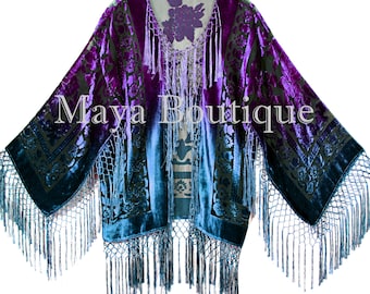 May include: A purple and teal silk kimono with a floral pattern and fringe trim. The kimono has a V-neck and is made of a soft, luxurious fabric. The text "Maya Boutique" is printed on the front of the kimono.