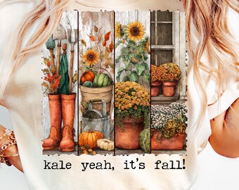 May include: Cream-colored t-shirt featuring a watercolor design of fall elements. The design includes pumpkins, sunflowers, gardening tools, and potted plants. The text "kale yeah, it's fall!" is printed below the image.