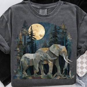 May include: Dark grey sweatshirt with a forest scene and two elephants under a full moon. The elephants are in shades of grey, green, and gold, with long white tusks. The background features tall pine trees and a large golden moon.