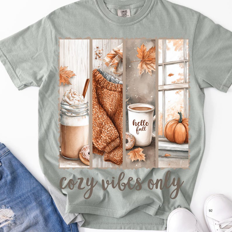 Pode incluir: Camiseta verde claro com um gr&aacute;fico tem&aacute;tico de outono. O gr&aacute;fico inclui um latte, um su&eacute;ter, uma caneca de caf&eacute; com o texto "hello fall" e uma ab&oacute;bora. As palavras "cozy vibes only" s&atilde;o impressas na parte inferior.