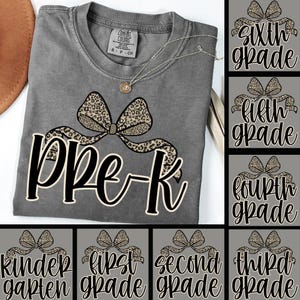 May include: Gray Comfort Colors t-shirt with a leopard print bow design and the text "Pre-K". A gold necklace is draped on the shirt. Additional designs for grades Kindergarten through Sixth Grade are also shown.