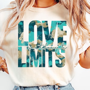 Op de afbeelding: Crèmekleurig T-shirt met de tekst "LOVE without LIMITS" in een teal en tan camouflagepatroon. De tekst staat gecentreerd op het shirt, met het woord "LOVE" boven "LIMITS". Het woord "without" is in cursief geschreven.