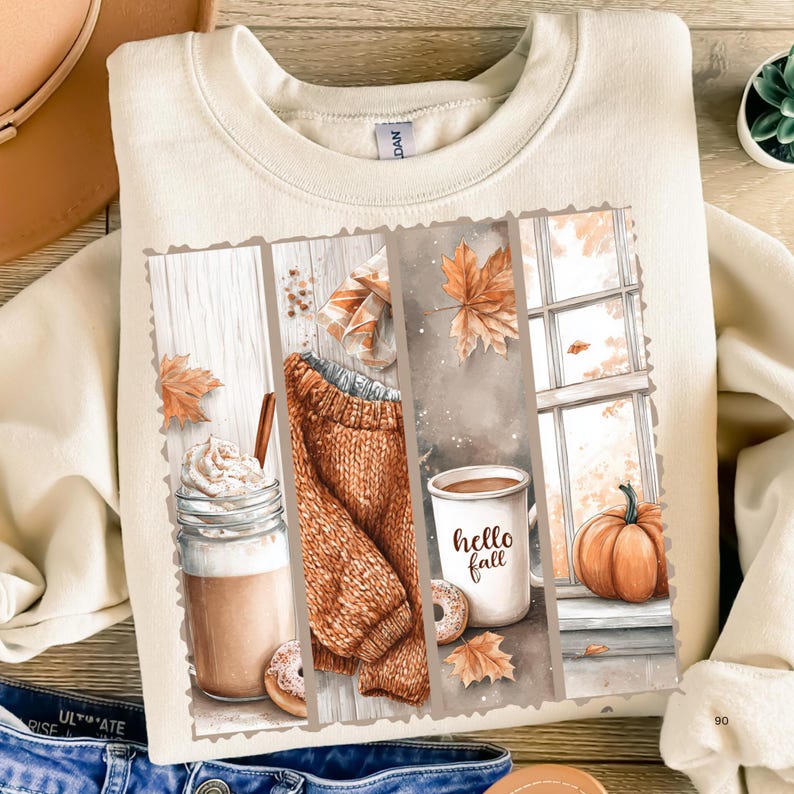Pode incluir: Camisola creme com um gr&aacute;fico com tema de outono. O design apresenta um su&eacute;ter aconchegante, caf&eacute;, uma ab&oacute;bora e as palavras "hello fall". O design incorpora folhas de outono e uma cena de janela.