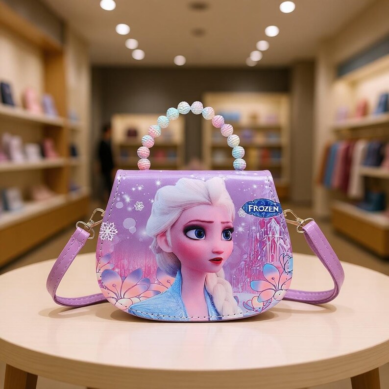 May include: A purple purse featuring a cartoon image of Elsa from the movie Frozen. The purse has a beaded handle with pastel-colored beads and a detachable shoulder strap. The design includes snowflakes and floral accents.