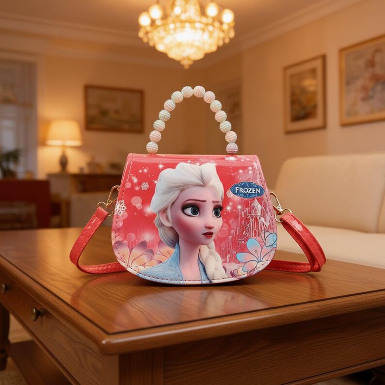 May include: A red and pink purse featuring a cartoon image of Elsa from the movie Frozen. The purse has a beaded handle and a red shoulder strap. The word "Frozen" is printed on the purse.
