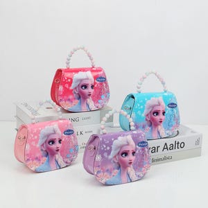 May include: Four colorful purses with beaded handles. Each purse features a portrait of a princess from the movie "Frozen". The purses are in pink, red, blue, and purple. The purses have a rounded shape and a small size.