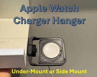 Op de afbeelding: Een zwarte Apple Watch-opladerhouder, gemonteerd onder een plank. De oplader heeft een vierkant ontwerp met een cirkelvormig oplaadpad. Tekst op de afbeelding luidt "Apple Watch Charger Hanger" en "Under-Mount or Side Mount."
