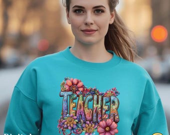 Könnte beinhalten: Ein türkisfarbenes Sweatshirt mit dem Wort "TEACHER" in farbenfrohen, floralen Buchstaben. Das Design zeigt verschiedene Blumen in Rosa-, Orange-, Gelb- und Lilatönen. Die Worte "Digital Download" befinden sich in der unteren linken Ecke.