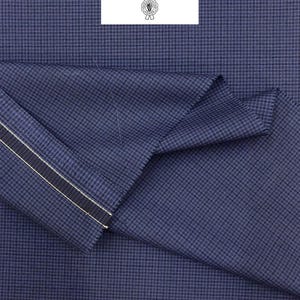 May include: Navy blue fabric with a small check pattern. The cloth is folded, showing a striped edge with white and gold details. The text "Cloth Ermenegildo Zegna" is on a white label.