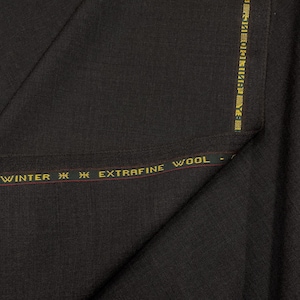 May include: Dark charcoal wool fabric with a subtle texture. A gold and red stripe along the edge reads "WINTER EXTRAFINE WOOL". The fabric is folded, showing the weave and drape of the material.