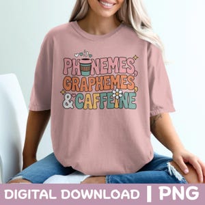 Puede incluir: Camiseta rosa claro con las palabras "Fonemas, Grafemas y Cafeína" en una fuente retro. El diseño incluye una taza de café, una flor y estrellas. La camiseta se combina con unos vaqueros azules.