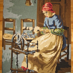 May include: A woman in a red cap sits in front of a spinning wheel, working on a piece of fabric. She is wearing a blue shirt and a beige skirt. The spinning wheel is made of wood and has a blue and white design. The background is a light blue and green color.