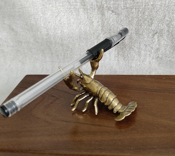 A solid brass lobster sculpted by hand that moonlights as a pen holder — the kind of absurdly charming desk object that becomes the first thing every visitor asks about.