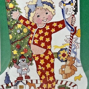 May include: A Christmas stocking with a cross-stitch design. The stocking features a child in star-patterned pajamas, a Christmas tree, and the text "I LOVE CHRISTMAS!". Other elements include a toy train, a robot, and a rocking horse.