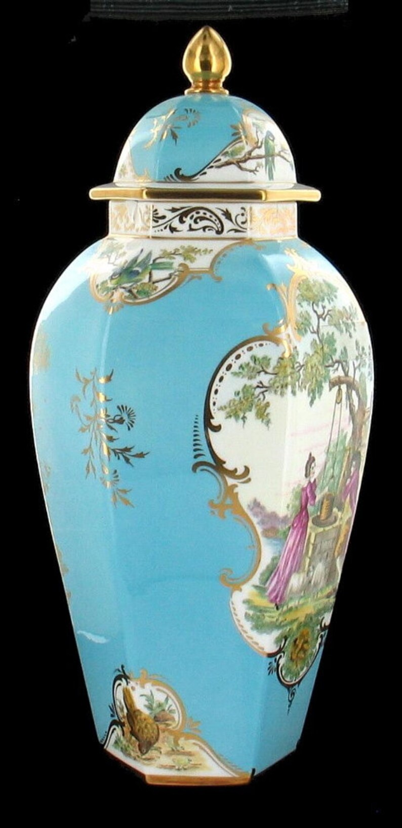 May include: A blue and white porcelain jar with a gold lid and intricate floral and bird designs. The jar has a octagonal shape and features a scene of a woman drawing water from a well.