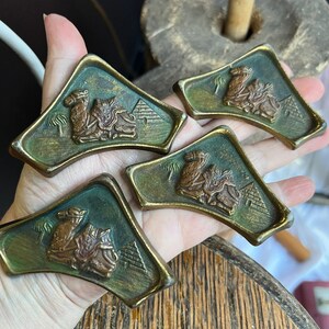 以下が含まれることがあります： ラクダとピラミッドのデザインが施されたアンティークな真鍮製の引き出しノブ4個。ノブは三角形で、緑色の緑青仕上げです。