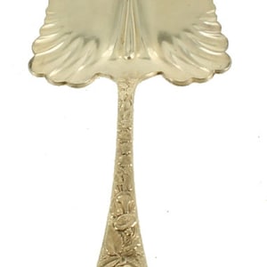 以下が含まれることがあります： 装飾的な花柄の銀製のケーキサーバー。サーバーは幅広で丸みを帯びた刃と長く細いハンドルを持っています。