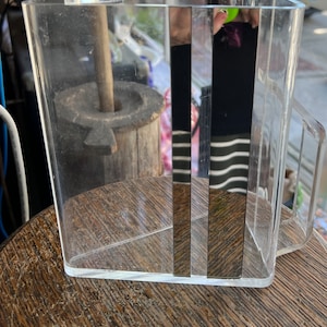 May include: A clear plastic container with a handle. The container has a mirrored surface on one side.