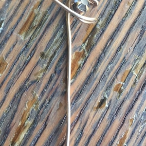 May include: A silver tie tack with a black gemstone in the center.