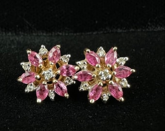 Könnte beinhalten: Ein Paar goldene Ohrringe mit rosa und weißen Edelsteinen. Die Ohrringe sind blumenförmig mit einem Cluster aus rosa Edelsteinen in der Mitte und weißen Edelsteinen am Rand.