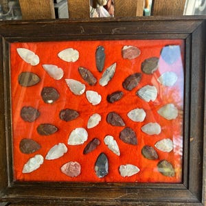 Colección antigua de puntas de flecha de nativos americanos del Atlántico Medio en vitrina enmarcada.