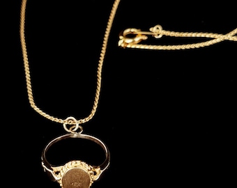 May include: A gold chain necklace with a gold ring pendant. The ring has a round, smooth surface.