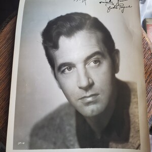 Puede incluir: Fotografía en blanco y negro de un hombre con una firma de "Jack Palance" debajo de la imagen. La firma dice "Atentamente, Jack Palance".