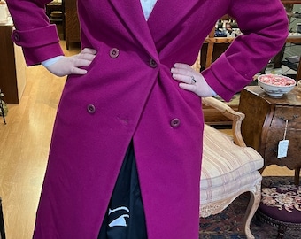 May include: A long, double-breasted, magenta wool coat with a classic collar and button closures.