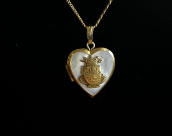 May include: A gold heart-shaped locket necklace with a white mother-of-pearl inlay and a gold crown design.