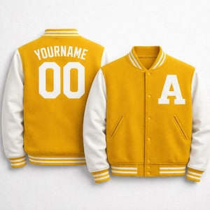 Puede incluir: Chaqueta universitaria de color amarillo mostaza con mangas blancas. La chaqueta presenta la letra "A" en la parte delantera y el texto "YOURNAME" y el número "00" en la espalda. La chaqueta tiene ribetes a rayas blancas y amarillas en el cuello, los puños y el dobladillo.