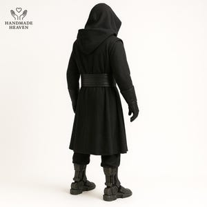 May include: A black hooded cloak with a wide belt, gloves, and boots. The cloak has a long, flowing design and is made of a dark fabric. The boots have a futuristic design. The Handmade Heaven logo is in the upper left corner.