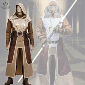 Puede incluir: Un disfraz de cosplay con una túnica con capucha en tonos beige y marrón. El disfraz incluye un cinturón con bolsillos y el logotipo de Handmade Heaven es visible. El atuendo se muestra en un maniquí.
