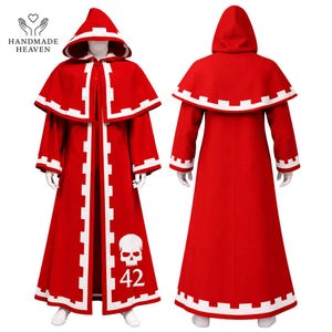 Peut inclure: Une cape rouge à capuche avec des bordures et des accents blancs. La cape présente un motif de crâne avec le numéro 42. Le logo Handmade Heaven est visible en haut à gauche. La cape est présentée de face et de dos.