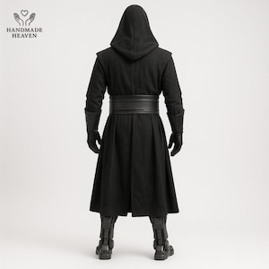 May include: A black hooded cloak with a wide belt, gloves, and boots. The cloak has a long, flowing design and is made of a dark fabric. The boots have a detailed, armored appearance. The Handmade Heaven logo is in the upper left corner.