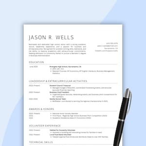 May include: A resume titled "JASON R. WELLS" with sections for education, leadership, awards, and volunteer experience. The resume includes contact information, a summary of skills, and details about extracurricular activities and honors. A black pen rests on the right side of the document.