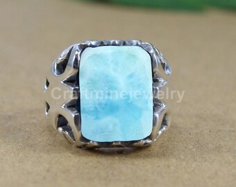 Könnte beinhalten: Ein silberner Ring mit einem rechteckigen, hellblauen Edelstein. Der Edelstein hat ein wolkiges Aussehen. Der Ring hat ein dekoratives, durchbrochenes Design an den Seiten. Der Text "Craftminejewelry" ist sichtbar.