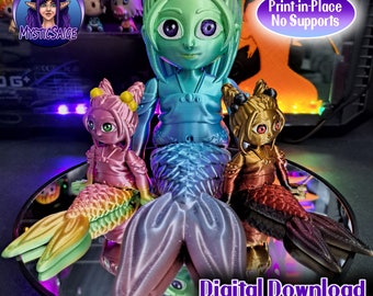 May include: Three 3D printed mermaid figurines. The largest mermaid is green with a blue tail and is wearing a blue and white kimono. The two smaller mermaids are pink and gold with rainbow and red tails. The text "Print-in-Place No Supports" and "Digital Download for 3D Printing" is visible in the image.