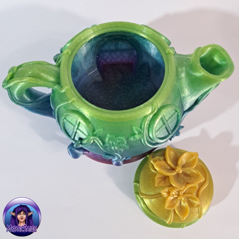 May include: A green and iridescent teapot with a floral design and a matching lid. The teapot has a round body with a spout and handle. The lid has a floral design with yellow flowers.