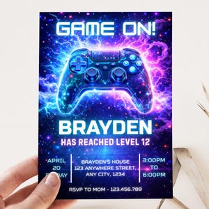 May include: A vibrant invitation with a gaming theme. The design features a glowing blue and purple controller against a starry background. Text includes "GAME ON!" and "BRAYDEN HAS REACHED LEVEL 12", along with event details.