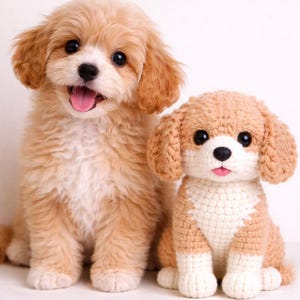 Op de afbeelding: Een echte puppy en een gehaakte hond zitten naast elkaar. De puppy heeft lichtbruine vacht, zwarte ogen en een roze tong. De gehaakte hond is bruin en wit met zwarte ogen en een roze tong.
