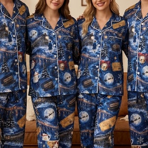 May include: Matching blue pajama sets featuring a festive holiday print with steam trains, golden train tickets, hot cocoa mugs, and silhouettes of Santa's sleigh against a moonlit sky. The button-down shirts have notched collars.