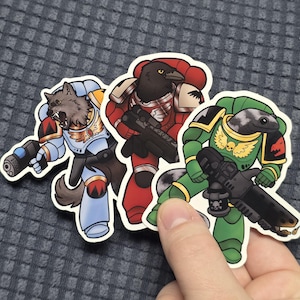May include: Three cartoon stickers featuring anthropomorphic characters in armor, each holding a weapon. The characters are a wolf, a raven, and a snake, each in different colored armor: blue, red, and green.