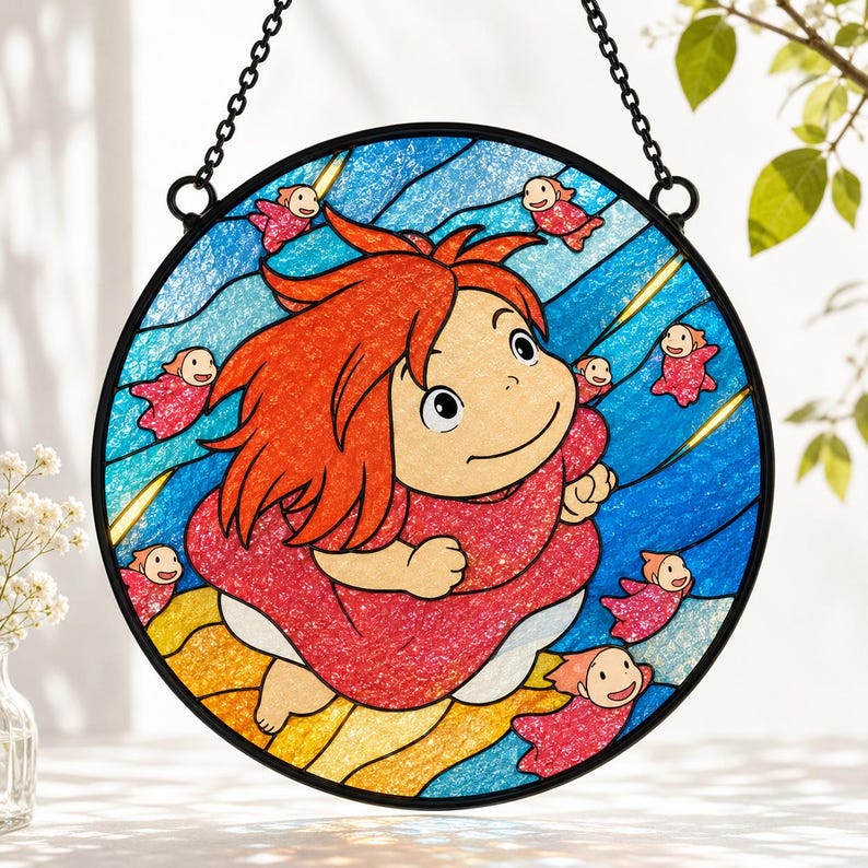 May include: A circular stained glass suncatcher featuring a central character with bright orange hair and a red dress, surrounded by small pink figures against a blue wavy background. The piece is framed in black metal and hangs from a chain.