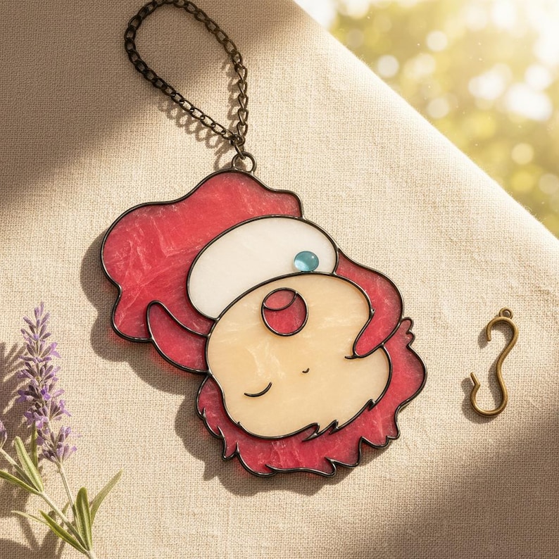 May include: A stained glass pendant featuring a cartoon character with red hair, a white hat, and a light skin tone. The pendant has a black outline and a small blue gem. A bronze-colored chain and hook are also visible.