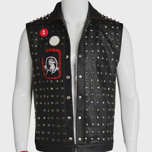 May include: Black leather vest with silver studs and a red and white patch. The vest has a collar and a button-up front. A red studded bracelet is on the mannequin's wrist. The vest is a punk rock style.