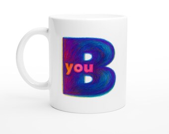 May include: White ceramic mug with a large, stylized letter "B" in shades of blue, purple, and pink. The word "you" is in orange, positioned within the "B". The mug has a curved handle.