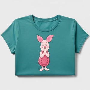 May include: Teal-colored t-shirt featuring a cartoon illustration of Piglet from Winnie the Pooh. Piglet is depicted with pink ears, a pink and red striped torso, and a smiling expression. The shirt has a crew neck and short sleeves.